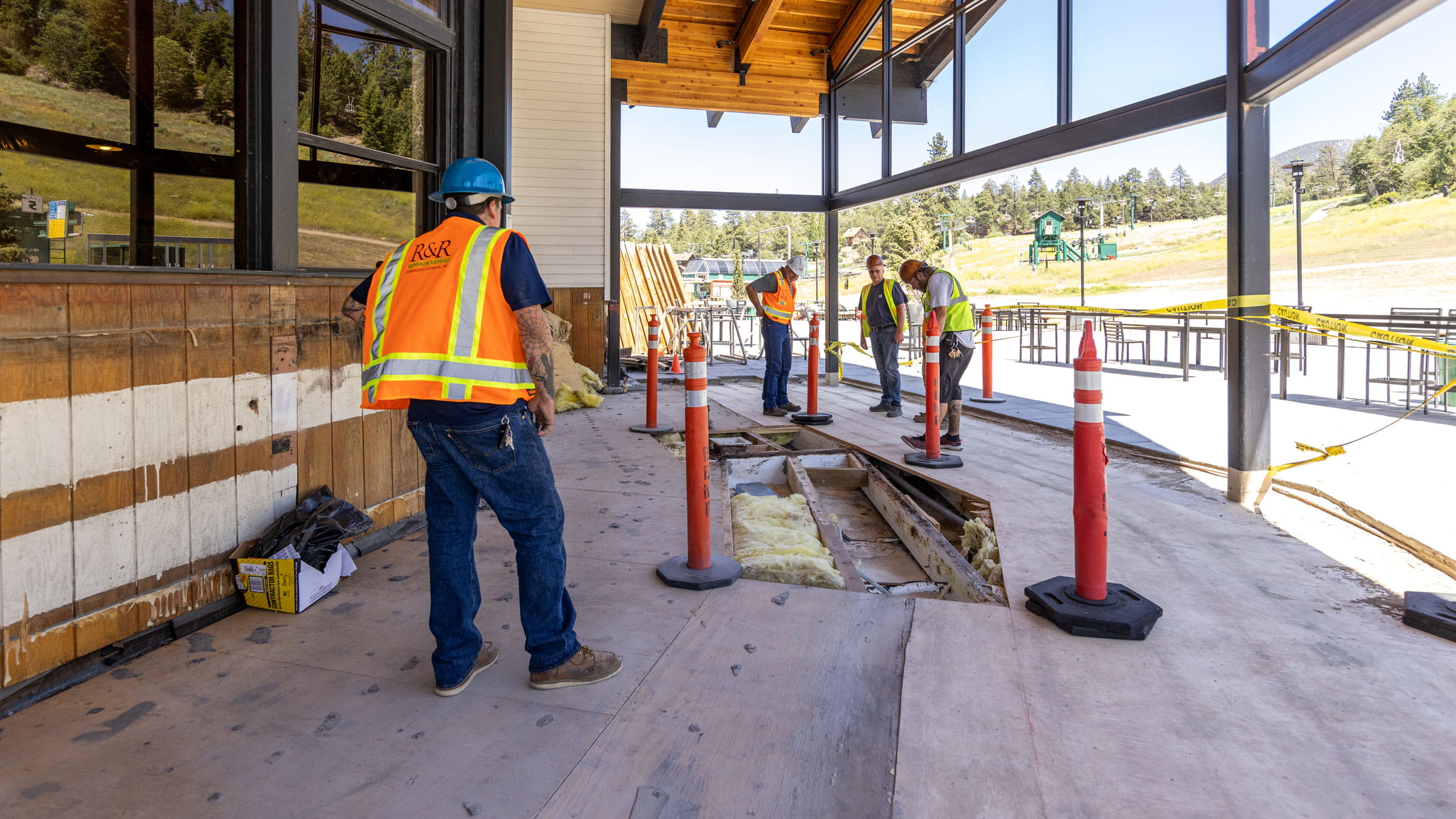 Construction workers with orange cones demolitioning a deck